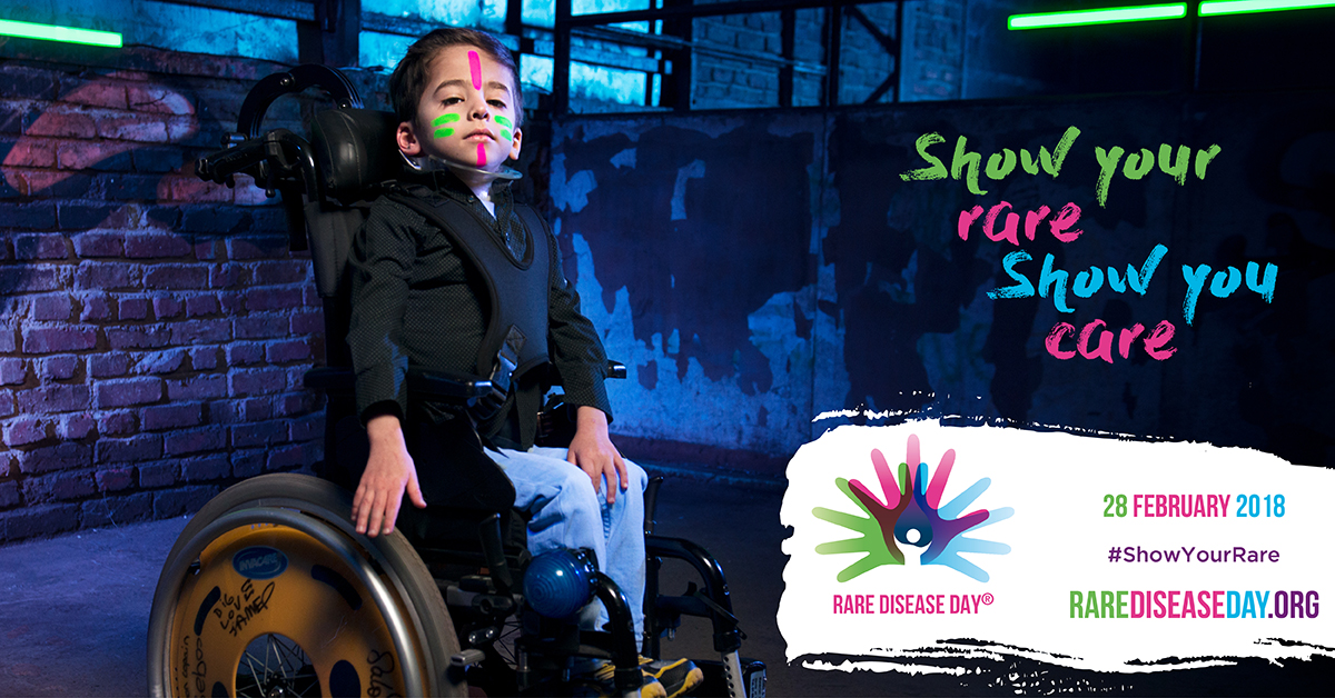 An image of Enzo in a wheelchair with pink and green stripes on his face. The text reads, 'Show your rare, Show you care'.