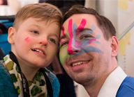 An image of a boy and a man with the rare disease logo painted on his face.