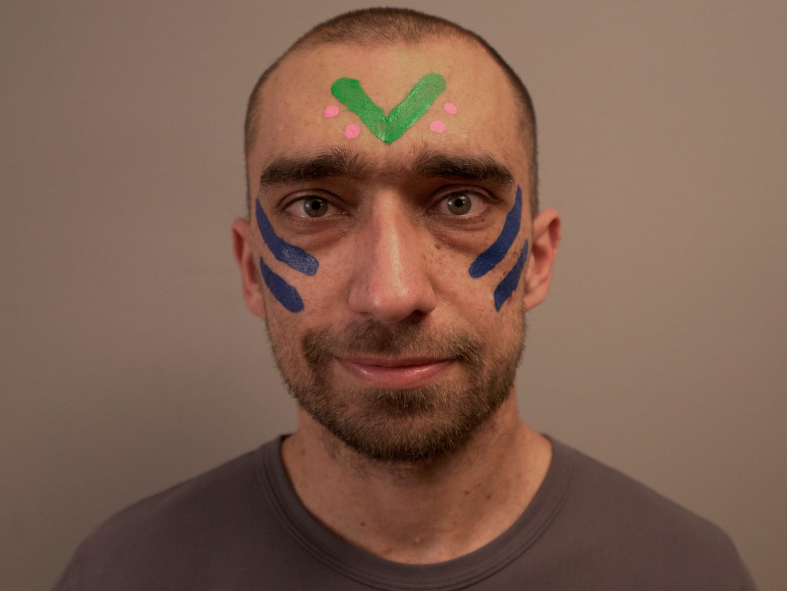 An image of Carlo with blue, green and pink painted stripes and dots on his face.