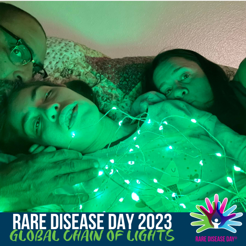 An image that shows a girl and her parents lying down wearing green lights. The text reads, 'Rare Disease Day 2023 Global Chain of Lights'. 