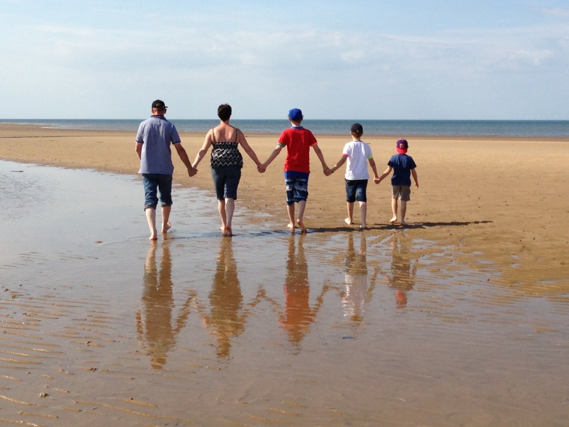 A family holding hands on the beach.