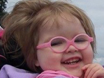 An image of a girl wearing pink glasses and smiling.