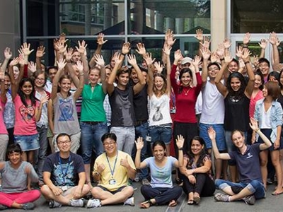 The image shows a group of people raising their arms with their palms open to mark rare disease day.