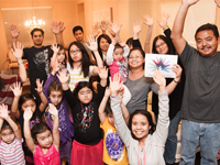 An image of children and adults raising their arms with a poster of the rare disease day logo to mark rare disease day.