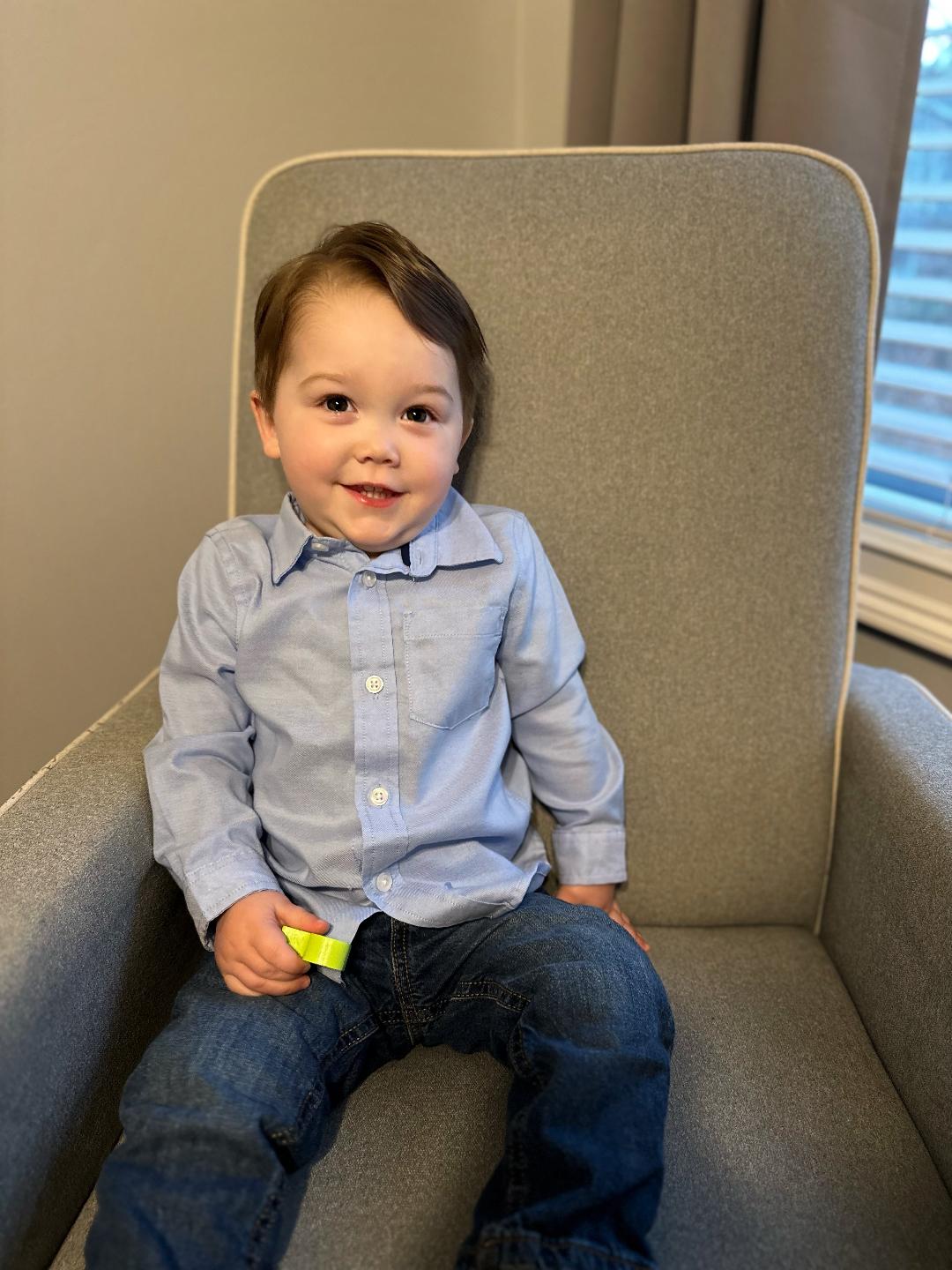 Young boy sitting comfortably in a sofa chair, featured in a hero story